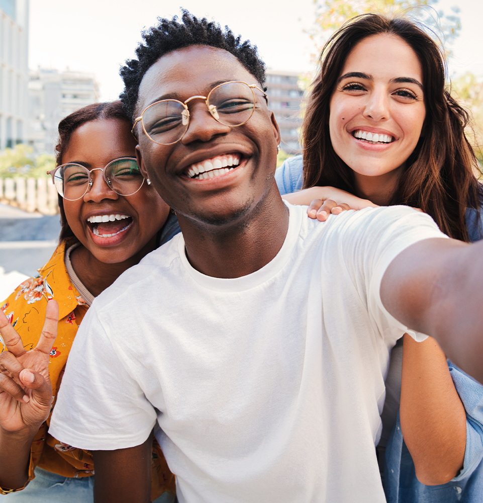 three smiling people outside